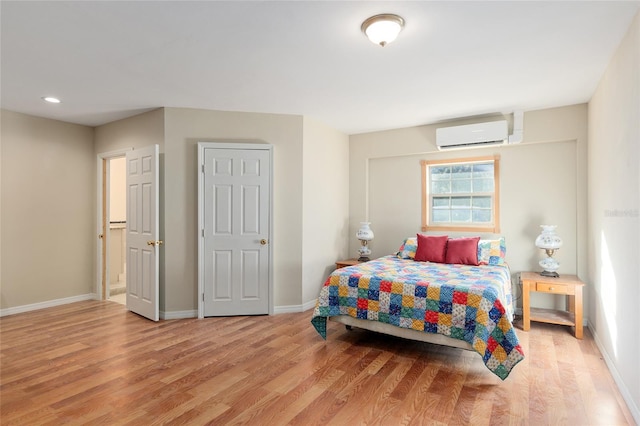 bedroom featuring a wall mounted air conditioner and light hardwood / wood-style flooring