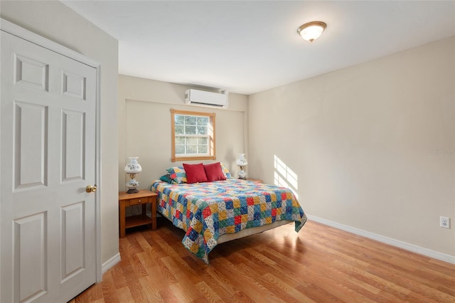 bedroom featuring light wood-type flooring and a wall mounted air conditioner