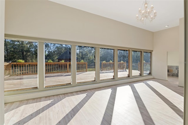 unfurnished living room featuring a wealth of natural light, a notable chandelier, and light wood-type flooring