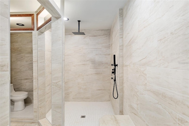 bathroom with a tile shower, toilet, and tile walls