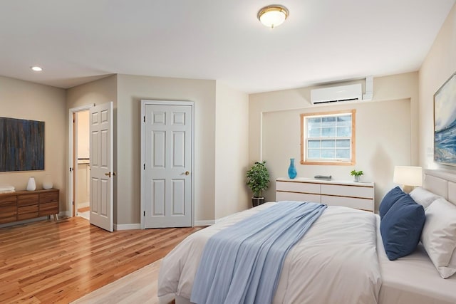 bedroom with an AC wall unit and light hardwood / wood-style flooring