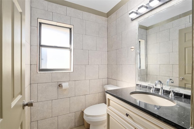 bathroom with toilet, vanity, and tile walls