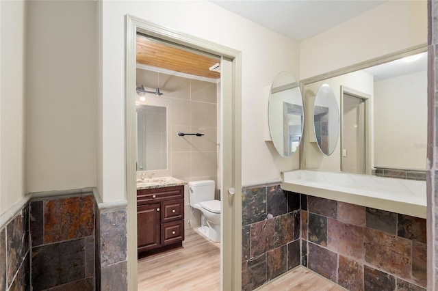 bathroom featuring hardwood / wood-style floors, toilet, vanity, and tile walls