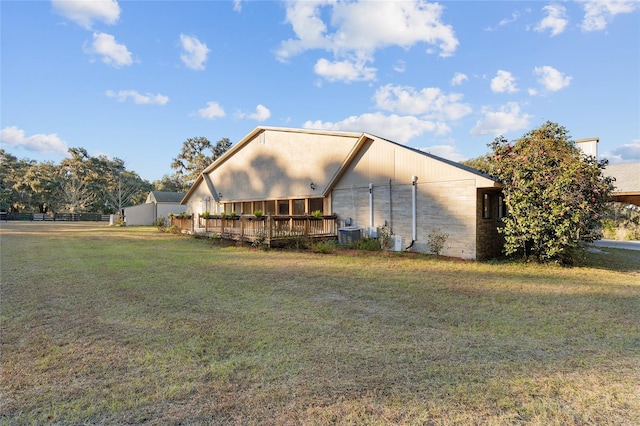 exterior space with a deck, central AC unit, and a lawn