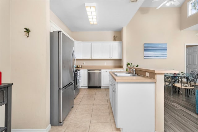 kitchen with a kitchen bar, sink, white cabinetry, and stainless steel appliances