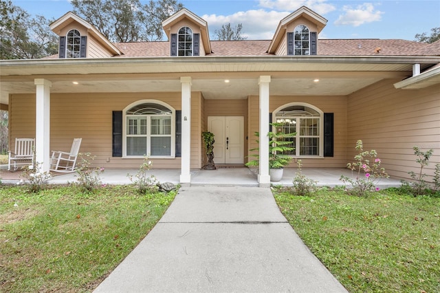 view of exterior entry with a yard and covered porch