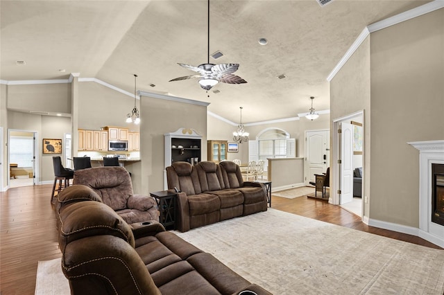 living room with lofted ceiling, ceiling fan, wood-type flooring, and ornamental molding