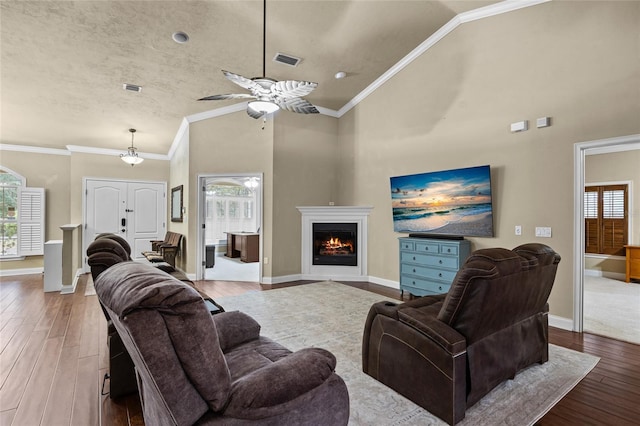 living room with a textured ceiling, hardwood / wood-style flooring, ceiling fan, and ornamental molding