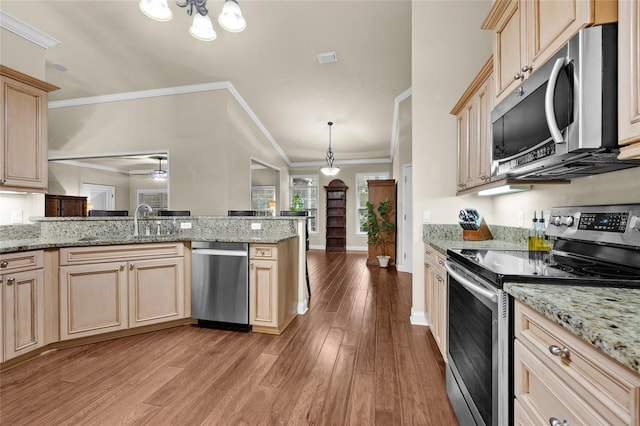 kitchen featuring kitchen peninsula, light brown cabinetry, light wood-type flooring, stainless steel appliances, and hanging light fixtures