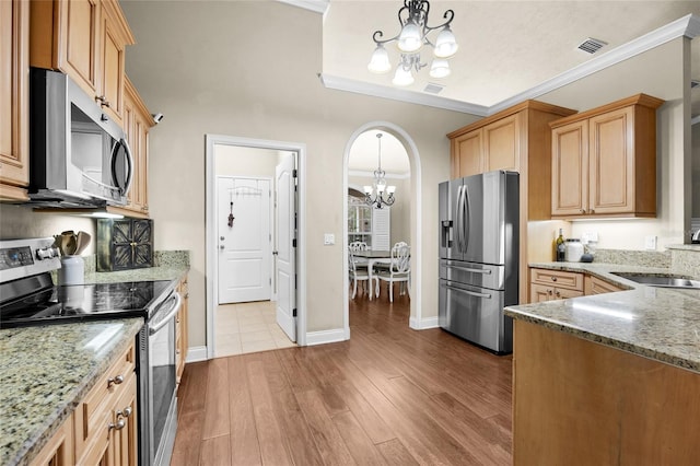 kitchen featuring light wood-type flooring, stainless steel appliances, sink, decorative light fixtures, and an inviting chandelier