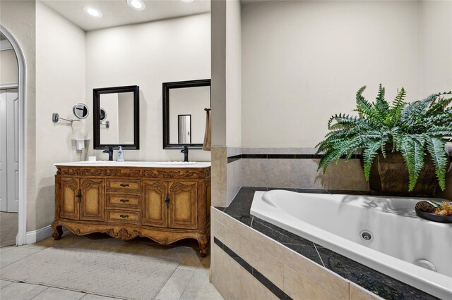 bathroom featuring tile patterned floors, a relaxing tiled tub, and vanity