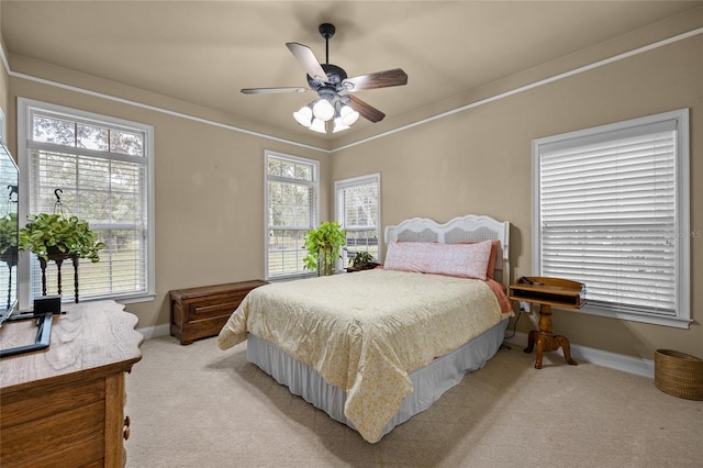 bedroom featuring ceiling fan, light colored carpet, ornamental molding, and multiple windows