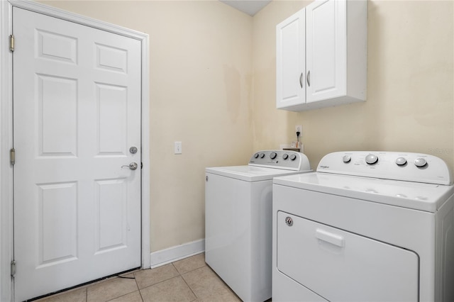 clothes washing area featuring washer and dryer, cabinets, and light tile patterned floors