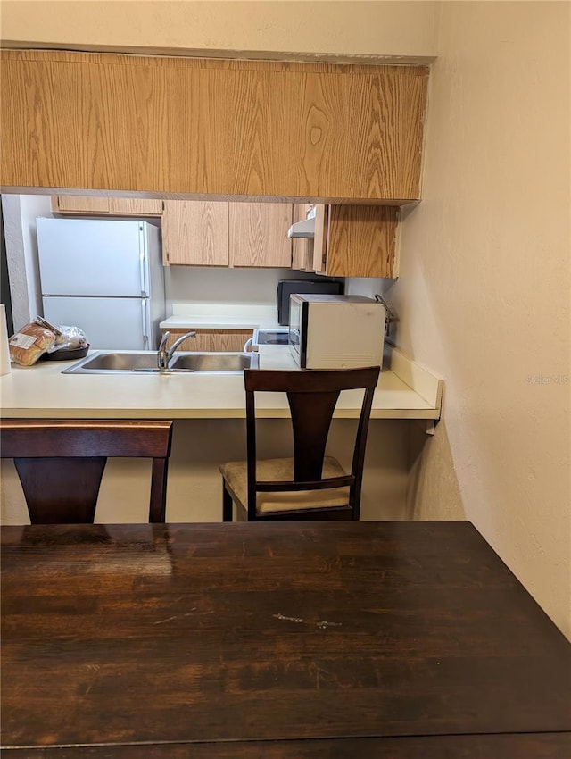 kitchen with white refrigerator, sink, and range hood