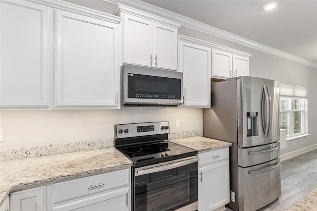 kitchen featuring light wood-type flooring, ornamental molding, appliances with stainless steel finishes, light stone counters, and white cabinetry