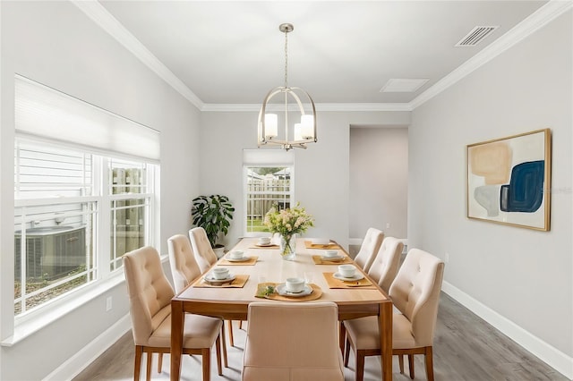 dining room featuring ornamental molding, hardwood / wood-style flooring, an inviting chandelier, and a healthy amount of sunlight