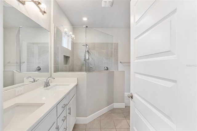 bathroom featuring tile patterned flooring, a tile shower, and vanity