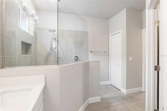 bathroom with a tile shower, tile patterned flooring, and vanity