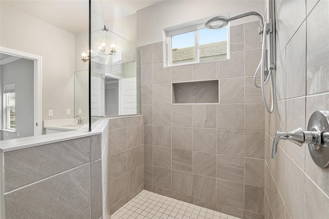 bathroom with tiled shower, an inviting chandelier, and sink