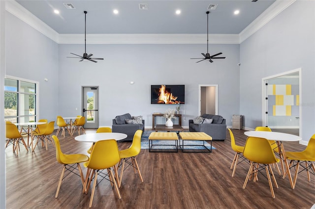 dining room with wood-type flooring, crown molding, and a towering ceiling