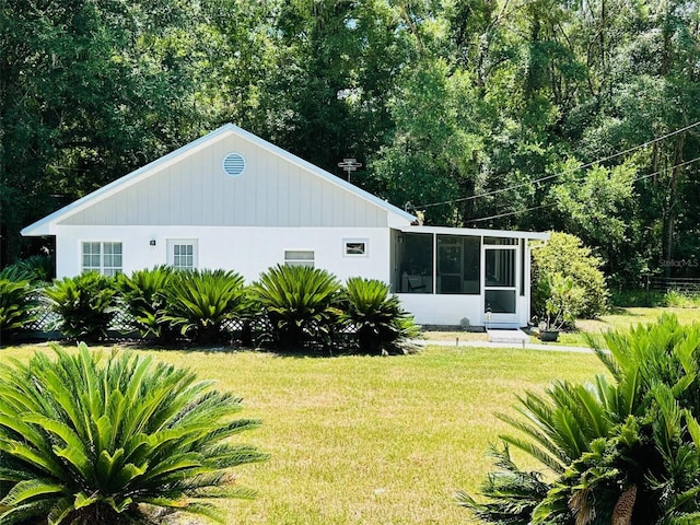 rear view of property featuring a sunroom and a lawn