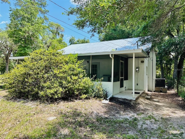 exterior space with central AC unit and a sunroom