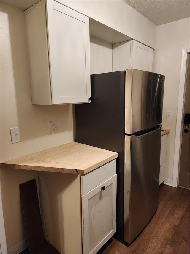 kitchen featuring a textured ceiling, dark wood-type flooring, butcher block countertops, white cabinetry, and stainless steel refrigerator