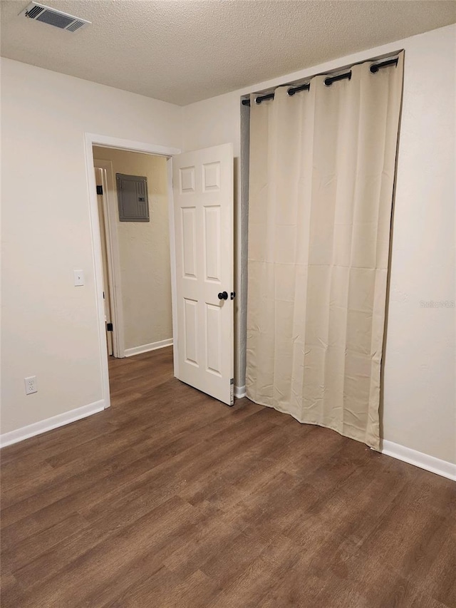 unfurnished bedroom with a textured ceiling and dark hardwood / wood-style flooring