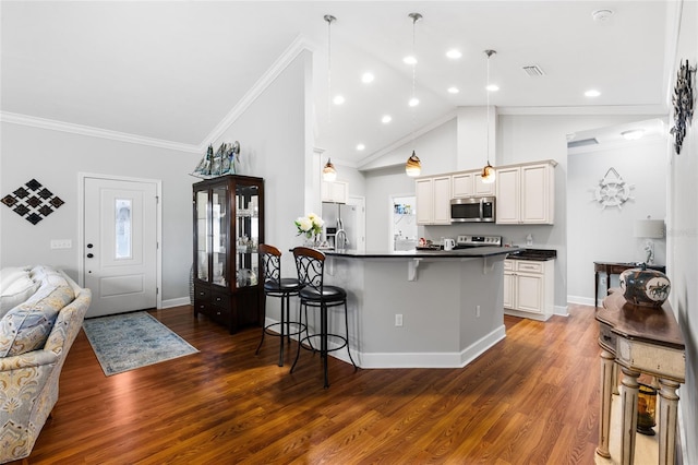 kitchen with kitchen peninsula, appliances with stainless steel finishes, decorative light fixtures, white cabinetry, and a kitchen bar