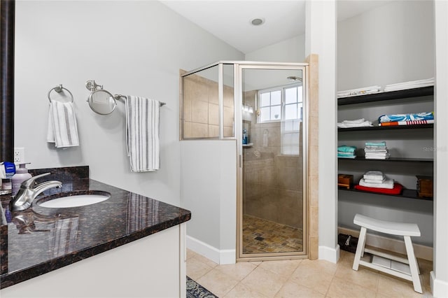 bathroom featuring a shower with shower door, vanity, lofted ceiling, and tile patterned flooring