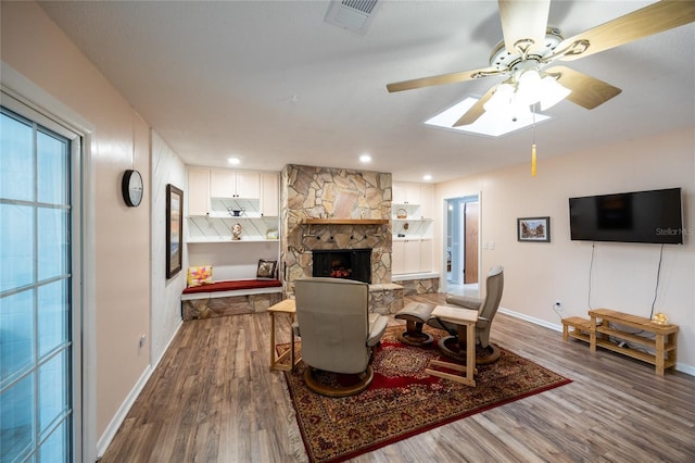 living room featuring ceiling fan, a fireplace, and wood-type flooring