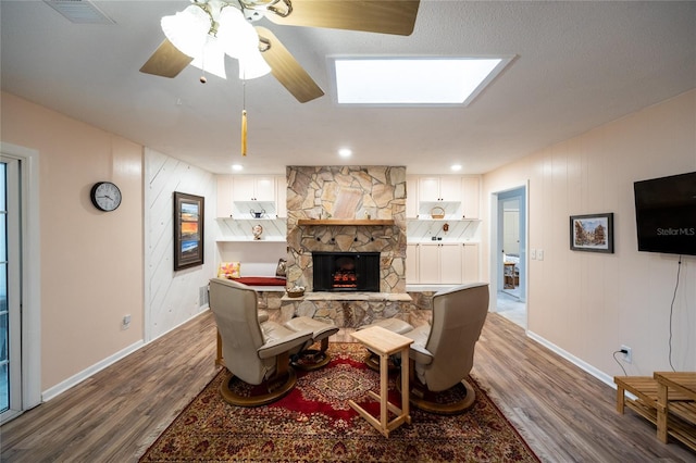 living room with ceiling fan, wood-type flooring, and a fireplace