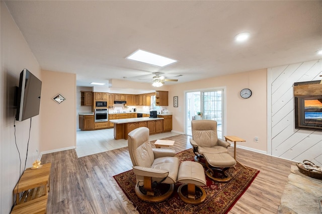 living room with wood walls, light hardwood / wood-style floors, and a skylight