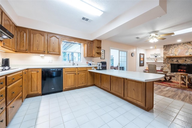 kitchen with black appliances, a stone fireplace, sink, ceiling fan, and kitchen peninsula