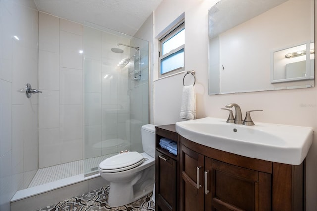 bathroom featuring tile patterned flooring, vanity, tiled shower, and toilet