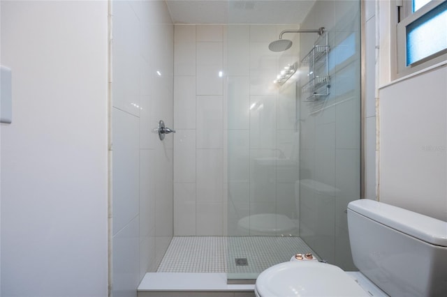 bathroom featuring toilet and a tile shower