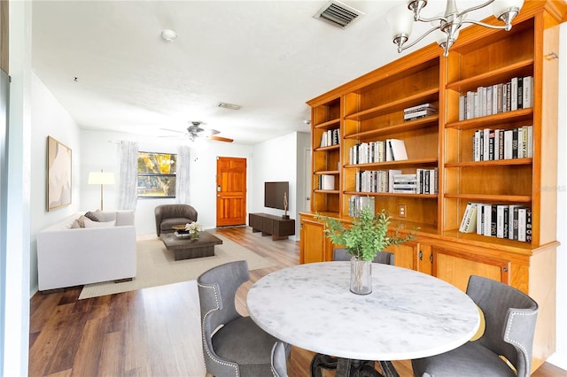 dining space with wood-type flooring and ceiling fan with notable chandelier