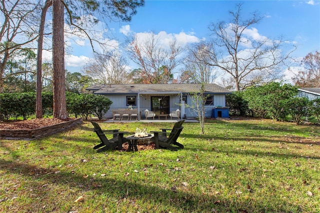 rear view of property with a lawn, a patio, and a fire pit