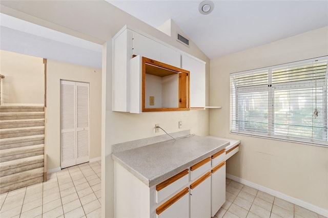 kitchen with light tile patterned floors, white cabinets, and vaulted ceiling