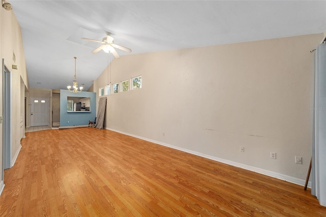 unfurnished living room featuring ceiling fan with notable chandelier, vaulted ceiling, and light wood-type flooring