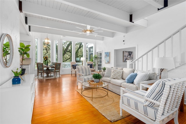 living room featuring ceiling fan, light hardwood / wood-style flooring, and beamed ceiling