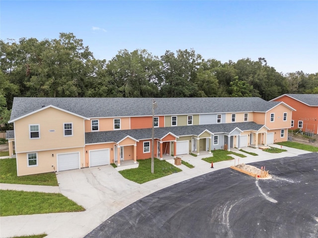 townhome / multi-family property featuring a residential view, roof with shingles, driveway, and an attached garage