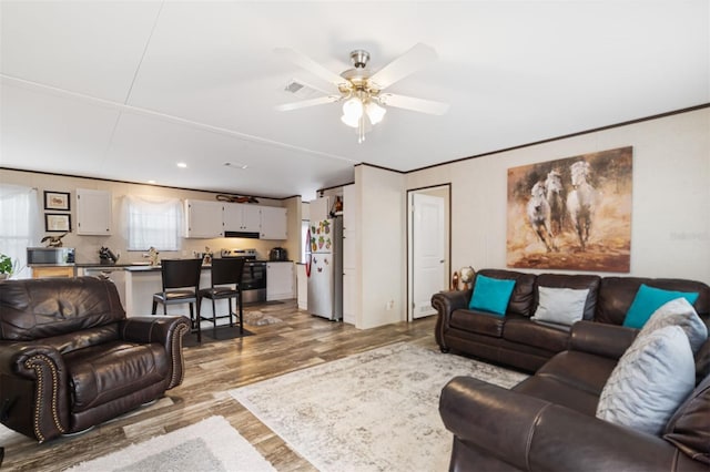 living room featuring hardwood / wood-style flooring, ceiling fan, crown molding, and sink