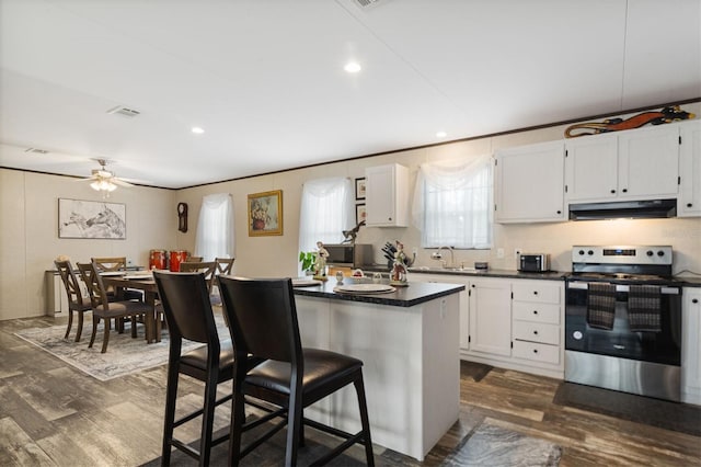 kitchen featuring a kitchen bar, dark hardwood / wood-style flooring, electric stove, a center island, and white cabinetry