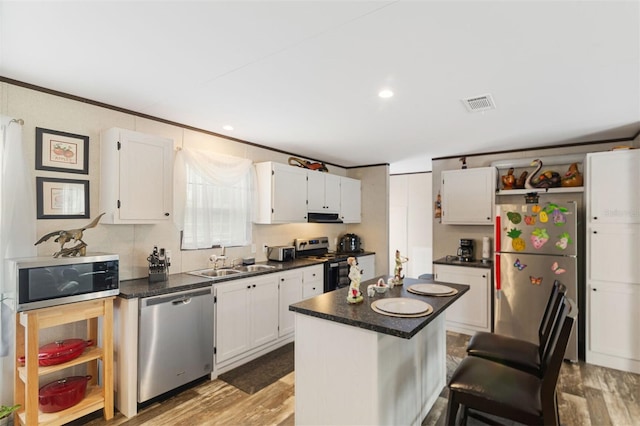 kitchen with a center island, stainless steel appliances, white cabinetry, and sink