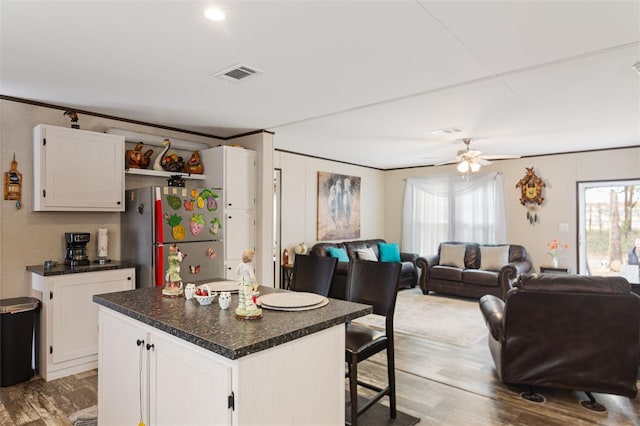 kitchen featuring ceiling fan, a center island, stainless steel fridge, white cabinets, and hardwood / wood-style flooring