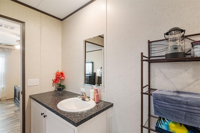 bathroom featuring vanity, ceiling fan, wood-type flooring, and crown molding