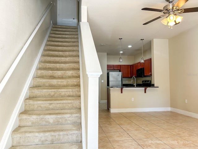 stairway featuring tile patterned flooring, ceiling fan, and sink