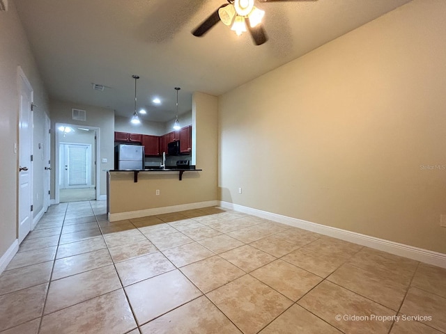 kitchen with ceiling fan, white fridge, pendant lighting, a breakfast bar, and light tile patterned flooring