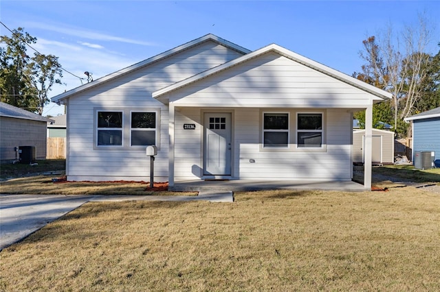 view of front facade featuring a front yard, a storage unit, cooling unit, and covered porch